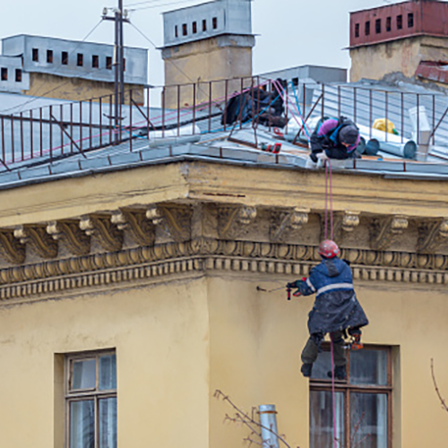 St. Petersburg, Russia - March 15, 2019: industrial climbers repair a drainpipe on the wall of a residential building in the city center